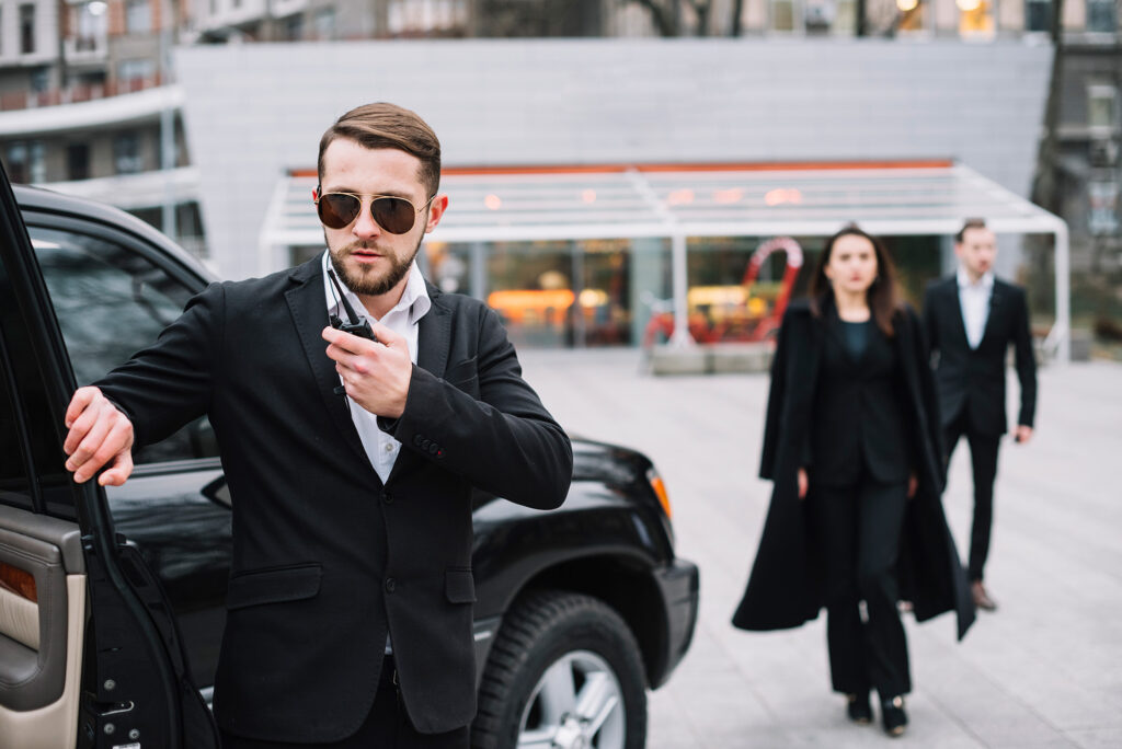 A man in black suit and sunglasses standing next to a woman.