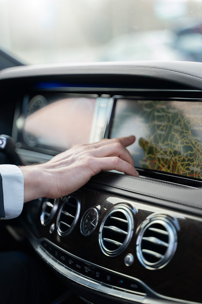 A person touching the center console of a car.